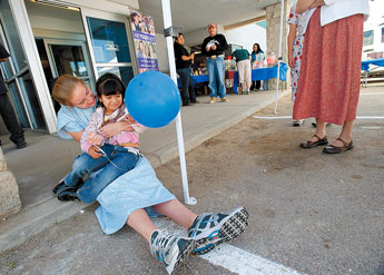 Katelyn Dyck of the Christian Children's Shelter embraces Tiffany Gray at the Children Youth and Families Department child abuse prevention open house in Gallup on Wednesday. Six-year-old Gray once a resident at the Children's shelter but now living a normal life with her mother and siblings. © 2011 Gallup Independent / Adron Gardner 